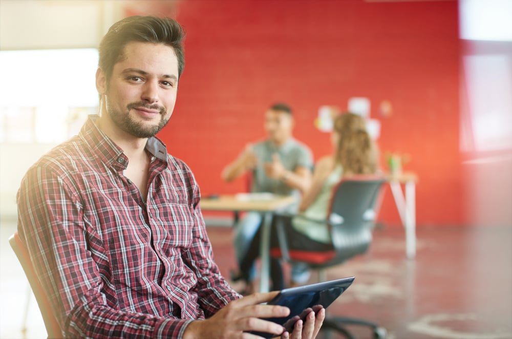 Confident male designer working on a digital tablet in red creative office space-1