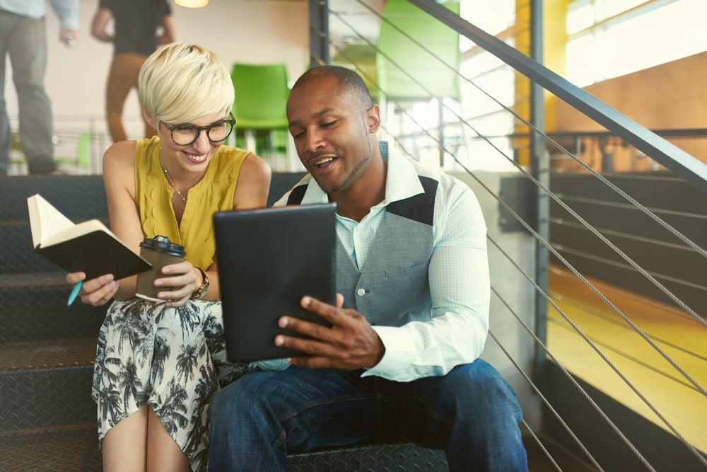 Two creative millenial small business owners working on social media strategy using a digital tablet while sitting in staircase-Mar-26-2024-05-23-14-5837-PM